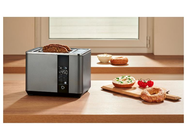Toaster mit Vollkornbrot, Bagels mit Frischkäse und Tomaten auf einer Holztheke.