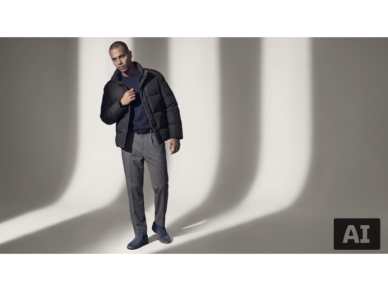 Mann in schwarzer Daunenjacke, blauem Pullover, grauer Hose und blauen Stiefeln.