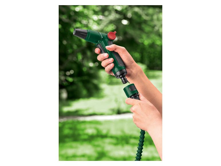 Hände verbinden einen grünen Gartenschlauch mit einer grünen Spritzpistole mit rotem Knopf.