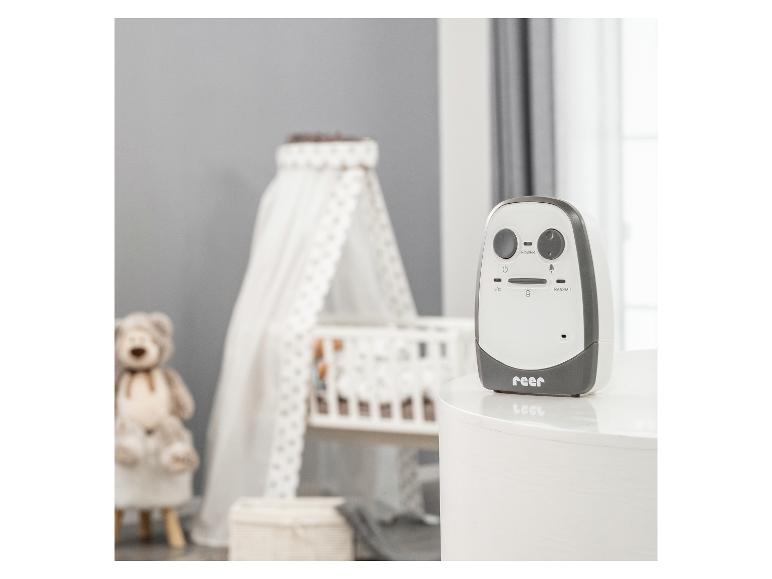 Babyphone auf einem weißen Tisch in einem Kinderzimmer mit Kinderbett und Teddybär.