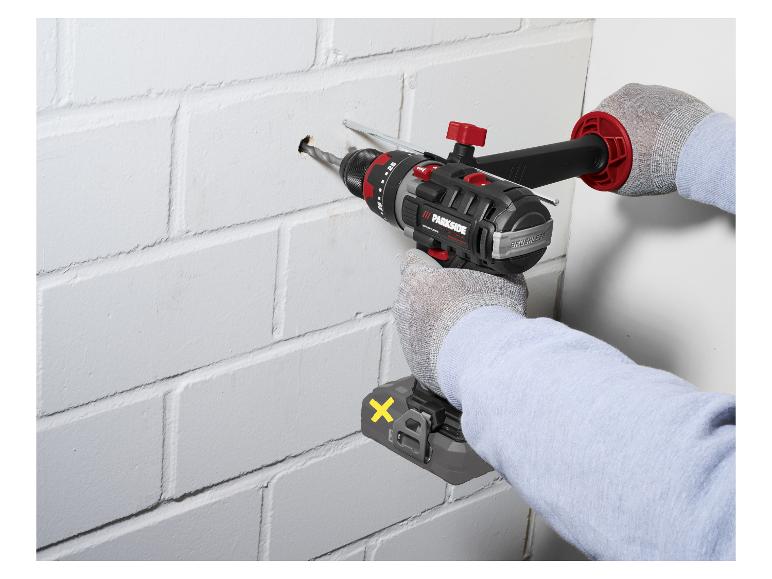 Person bohrt ein Loch in eine weiße Ziegelwand mit einem Akku-Bohrschrauber.