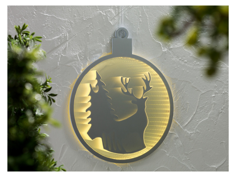 Eine runde, weiße Weihnachtsdekoration mit einem Hirsch und einem Baum.