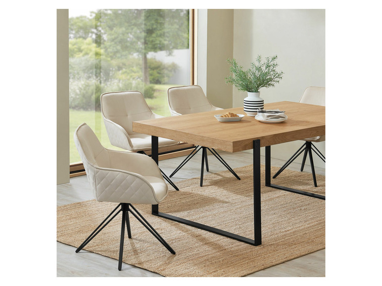 Ein Holztisch mit vier beigefarbenen Stühlen mit schwarzen Beinen.