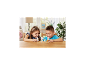 Zwei lächelnde Kinder spielen mit Tierfiguren an einem Holztisch.