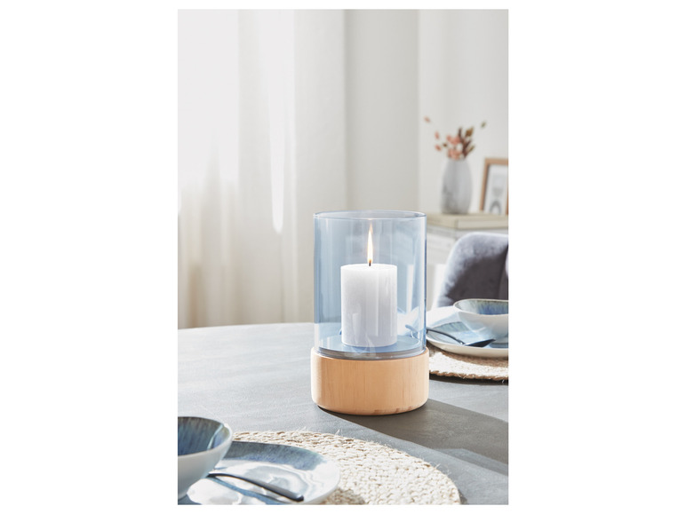 Ein blauer Glas-Kerzenhalter mit Holzfuß auf einem Tisch