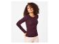 Frau in bordeauxrotem Langarmshirt mit Rippstruktur und heller Hose.