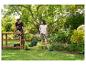 Paar im Garten mit Rasenmäher, Trimmer und Grasschere.