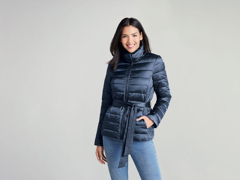 Eine Frau trägt eine dunkelblaue Steppjacke mit Gürtel.