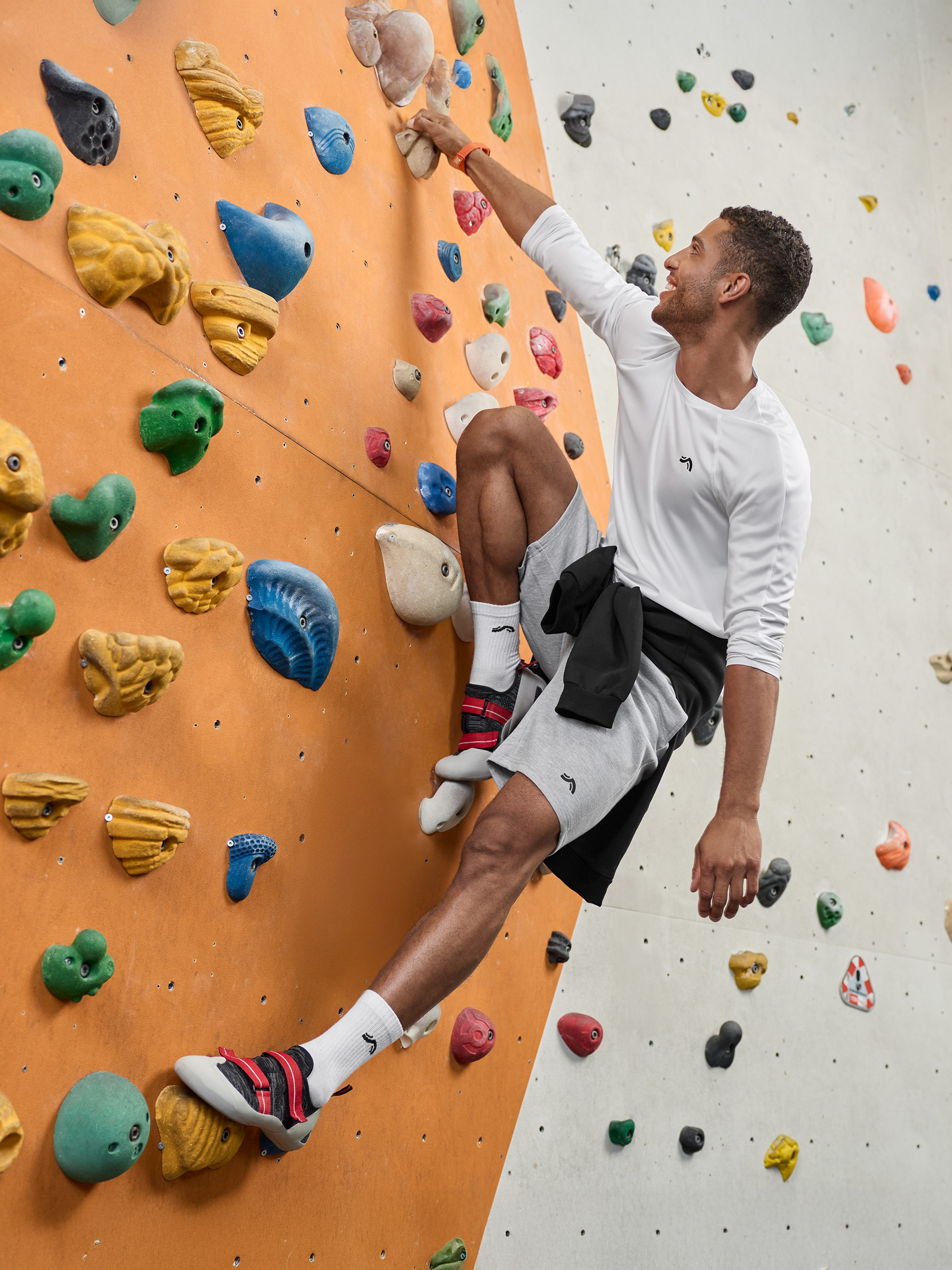 Mann in Crivit Langarmshirt und Shorts beim Indoor-Klettern.