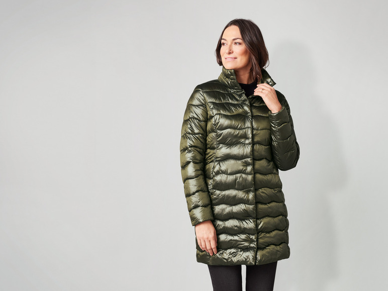 Eine Frau trägt einen langen, grünen, gesteppten Mantel.