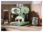 Minzfarbene Kaffeemaschine mit zwei Espressotassen auf einer Holzarbeitsplatte.