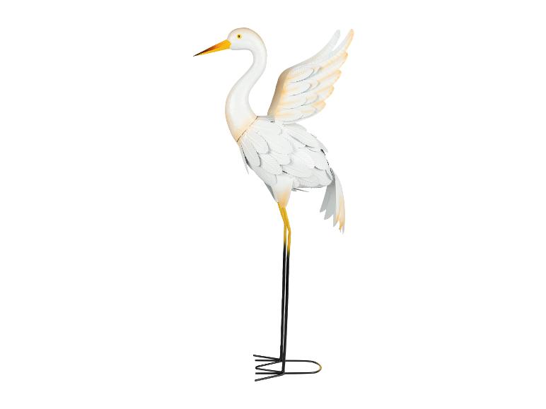 Eine weiße Metallskulptur eines Reiher mit ausgebreiteten Flügeln.