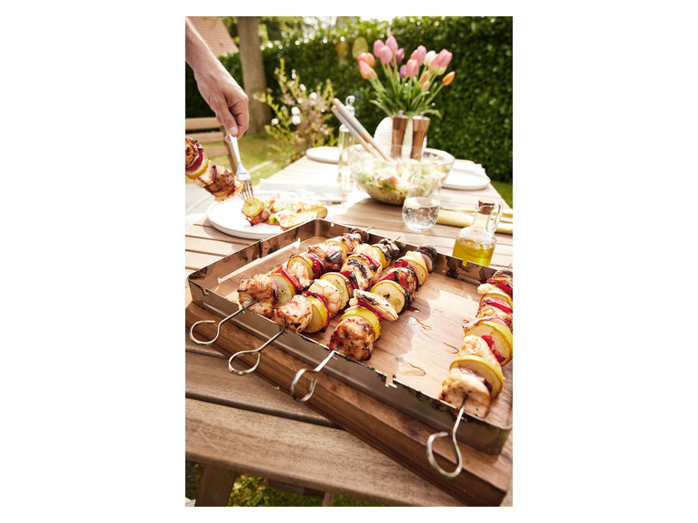Gegrillte Spieße mit Hühnchen, Paprika und Zucchini auf einem Holzbrett.