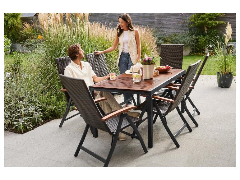 Paar sitzt an einem Gartentisch mit Rattan-Stühlen auf einer Terrasse.