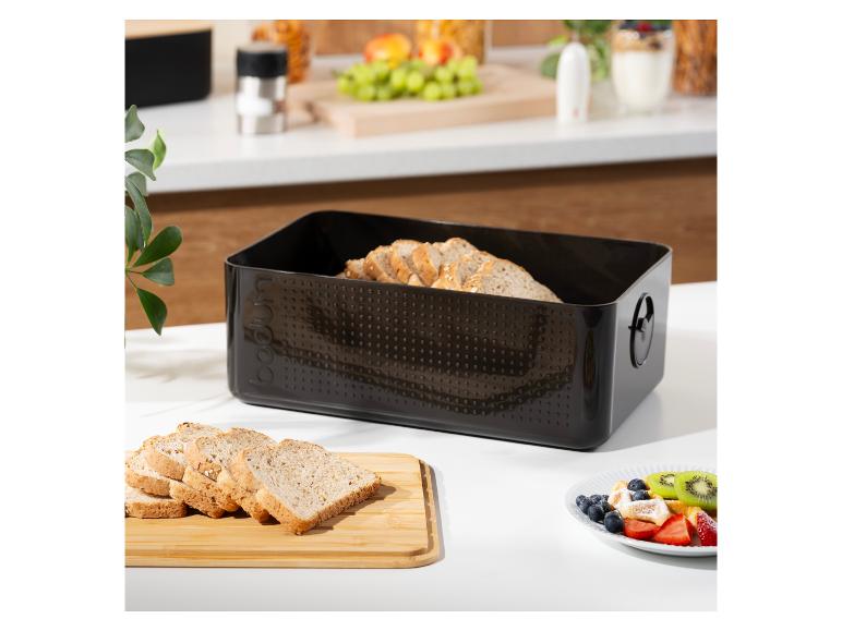 Schwarzer Brotkasten mit geschnittenem Brot und Frühstück auf einer Küchentheke.