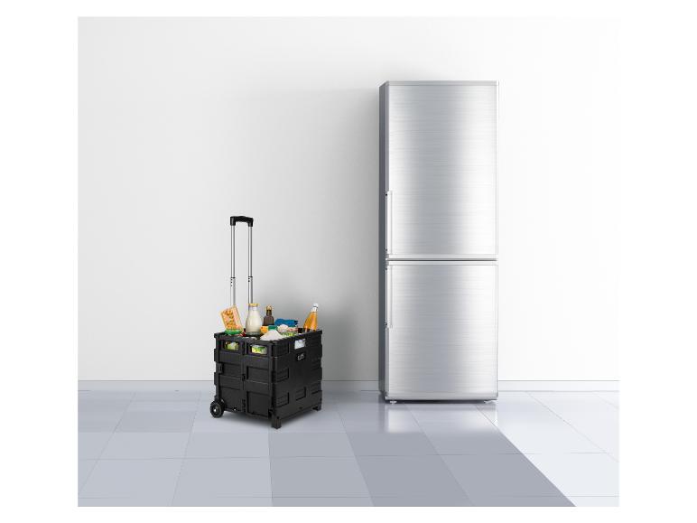 Schwarzer faltbarer Einkaufswagen mit Lebensmitteln neben einem silbernen Kühlschrank.