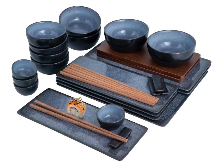 Ein Stapel blaue Keramik-Schalen, Teller und Essstäbchen mit einer Sushirolle