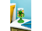 Grüne Nachtlampe mit Computerspiel-Motiv auf einem weißen Nachttisch.