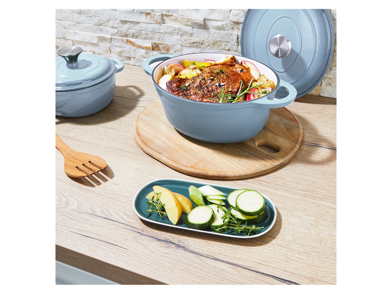 Blaue gusseiserne Töpfe mit Braten und Gemüse.