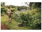 Frau bewässert Garten mit Gartenschlauch und Schlauchtrommel.