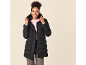 Lächelnde Frau in schwarzer Steppjacke und rosa Pullover, die die Kapuze der Jacke hält.
