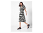 Model in schwarzem Kleid mit weißem Muster und schwarzen Sandalen.