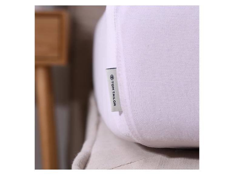 Weißes Tom Tailor Kissen mit Etikett in Innenräumen.