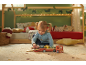 Kleines Kind spielt mit Holzspielzeug-LKW mit Autos im Kinderzimmer.