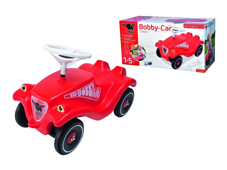 Rotes Spielzeugauto mit weißem Lenkrad und seine Verpackung mit deutschem Text.