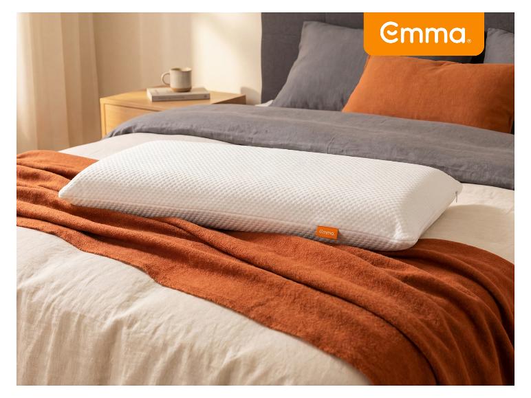 Weißes strukturiertes Kissen auf einer orangefarbenen Decke und grauer Bettwäsche in einem Schlafzimmer