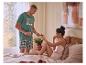 Mann in kariertem Pyjama und 'Sunday Mood' T-Shirt bietet Frau im Bett Obst an.