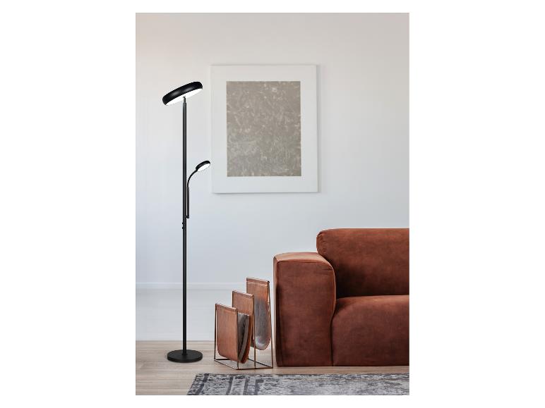 Moderne Stehlampe mit zwei Lichtern neben einem braunen Sofa und einem Leder-Zeitschriftenständer.