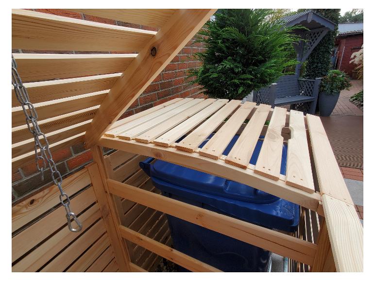 Ein Holz-Abfallbehälter mit einem blauen Mülleimer im Inneren