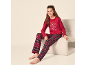 Mädchen in rotem Pyjama mit „Let's have breakfast“-Aufdruck und karierter Hose, sitzt auf einem Stuhl.