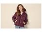 Frau in burgunderfarbener Steppjacke mit Kapuze und Jeans