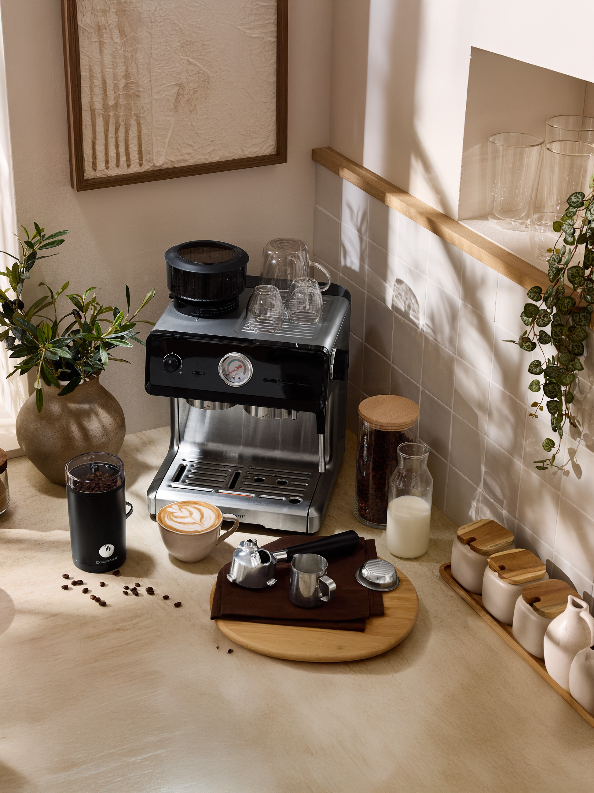Kaffeemaschine mit Mühle, Latte Macchiato Tasse und Zubehör auf einer Küchenarbeitsplatte.