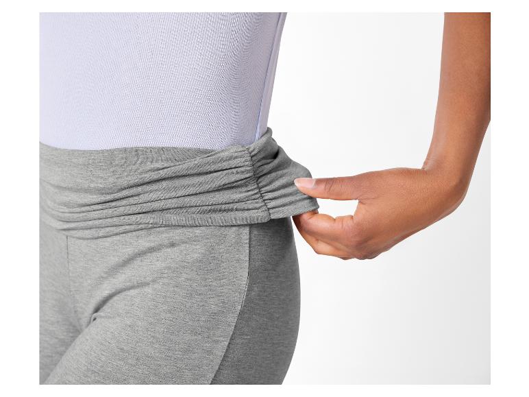 Frau in grauen Leggings mit gerafftem Bund und hellviolettem Oberteil.