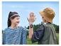 Zwei Kinder in gestreiften T-Shirts und Fischerhut geben sich High-Five, eines trägt eine Smartwatch.