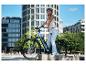 Lächelnde junge Frau mit Helm auf einem E-Bike in der Stadt.