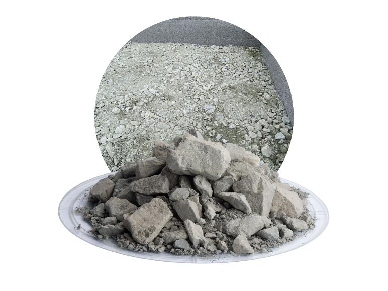 Ein Haufen grauer Steine auf einem durchsichtigen Teller, mit einem runden Hintergrund aus steinigem Boden.