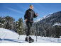 Frau in schwarzer Jacke und Leggings mit Stöcken in verschneiter Berglandschaft