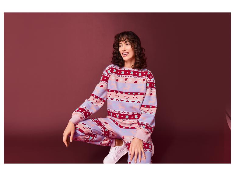 Eine Frau trägt einen rosa Weihnachtspullover und eine passende Hose.