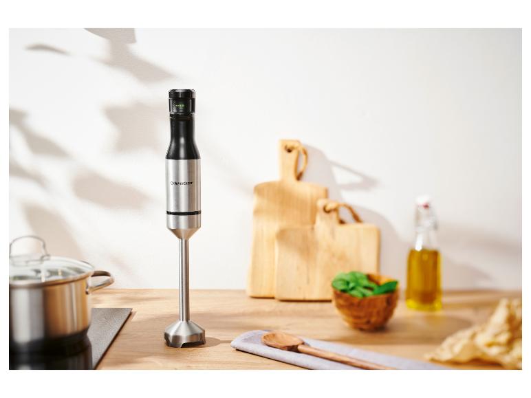 Ein SilverCrest Stabmixer auf einer Küchenarbeitsplatte mit Topf und Kochutensilien.