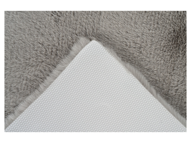 Ein grauer, flauschiger Teppich mit einer weißen Anti-Rutsch-Unterseite.