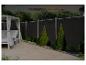 Außenbereich mit Tagesbett, dunklem Zaun mit integrierter Beleuchtung und grünen Sträuchern.