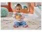 Baby sitzt auf einem Teppich und spielt mit einem orange-blauen Hasen-Beißspielzeug.