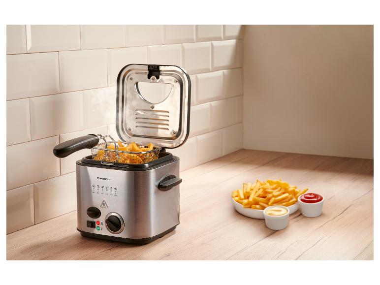 Fritteuse mit Pommes Frites und Saucen auf einer Holztheke.