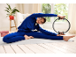 Frau in blauem Trainingsanzug macht Pilates mit einem Pilatesring auf einer Matte.