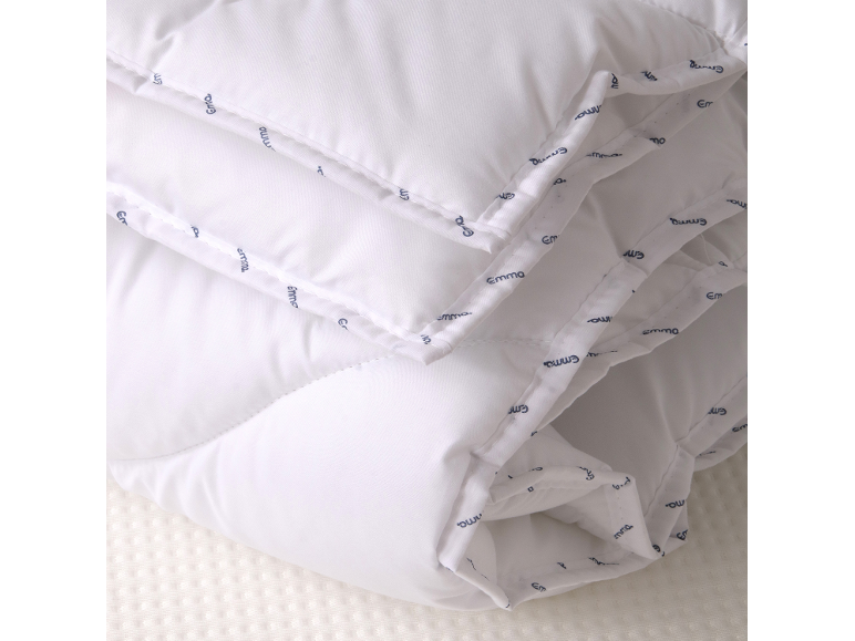 Weiße Steppdecke mit blauer „Emma“-Aufschrift am Rand.