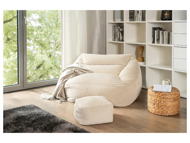 Beiger Cord-Sitzsack und Hocker mit Decke, grauem Teppich und weißem Bücherregal am Fenster